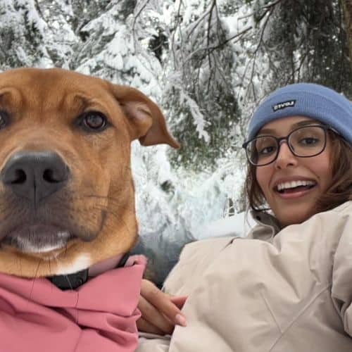 Ravleen in the snow with a brown dog.